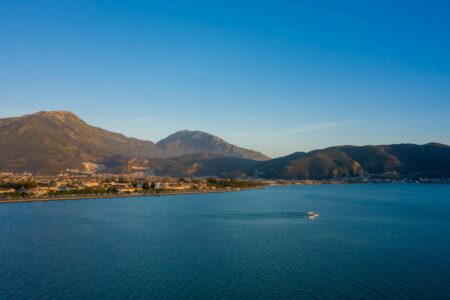 A breathtaking aerial view of a coastal town with mountains and a tranquil sea.